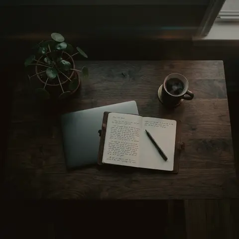 Aufgeschlagenes Notizbuch, Tablet und Kaffee auf dunklem Holzschreibtisch